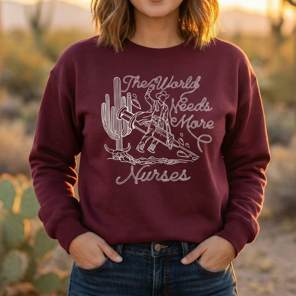 Woman wearing a maroon sweatshirt with a graphic and text, standing in a desert landscape with cacti.